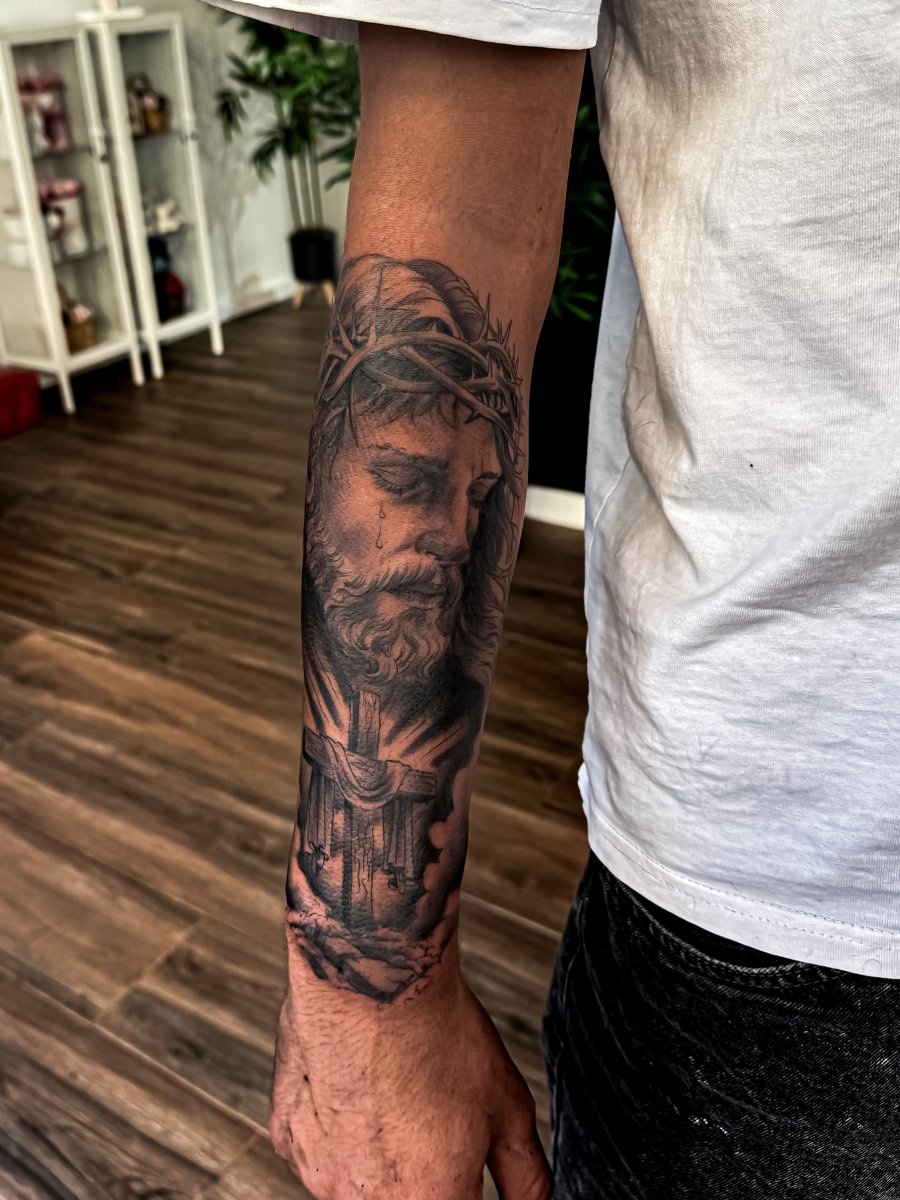 Tatuagem realista religiosa no antebraço